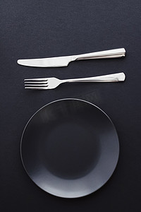 黑色背景的空盘子和银器、节日晚餐的优质餐具、简约的设计和饮食