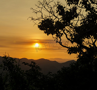 夕阳西下，山后的天空是橙色的，远处的山反射着橙色的光芒。