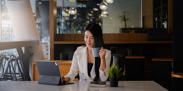 一位高管女商人顾问、代理人、代表的肖像，他们拿着一杯咖啡，通过数字平板电脑进行视频通话。