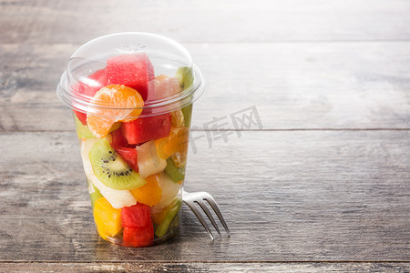 木桌上塑料杯中的鲜切水果