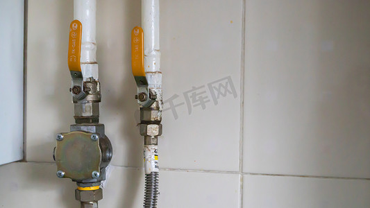 现代家庭锅炉房内的黄色阀门和天然气管道位于带瓷砖的厨房里。