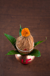 卡拉什摄影照片_铜卡拉什用椰子和芒果叶与花卉装饰在木质背景。