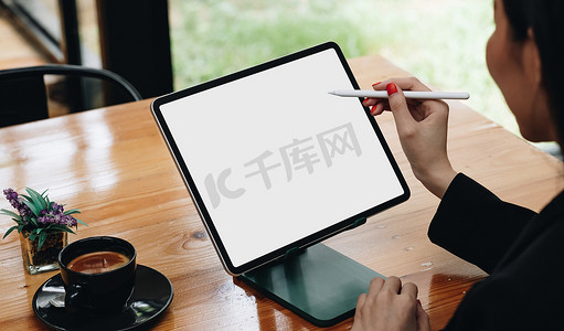 女性自由职业者手持手写笔指向空白白屏数字平板电脑屏幕的侧视图