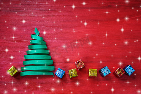彩带圣诞树礼物摄影照片_圣诞树由绿色丝带制成，红色背景上有小礼物。