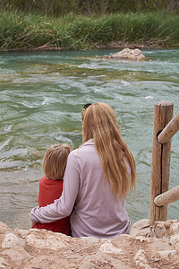 孩子和妈妈睡摄影照片_母亲和儿子看着汹涌的河流