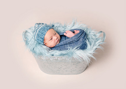 刚出生的婴儿躺在水槽里，上面铺着一条蓝色毯子