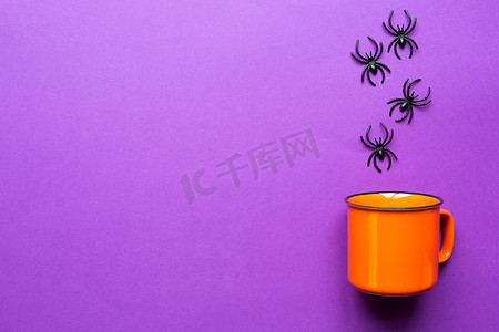 紫色杯子摄影照片_紫色背景上的橙色杯子与蜘蛛。