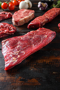 替代的 Flank bavette 或 flap steak beef t steak near tri-tip 和 top blade oyster cuts close in front in other cuts in butchery on old wood table side view 垂直