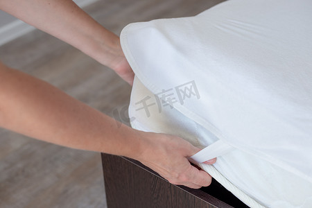 女人整理床铺，在床垫上盖上防水保护罩。