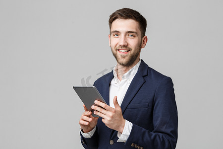 经营理念-肖像英俊的商人玩数字平板电脑与自信的笑脸。
