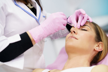 医生通过在病人的鼻子里注射透明质酸来进行隆鼻手术。