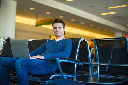 在机场等待航班时携带笔记本电脑的年轻人