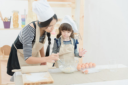 亚洲母亲和她的女儿正在准备面团，在厨房里度假做蛋糕