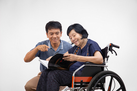 老妇人坐在轮椅上和儿子一起看书。