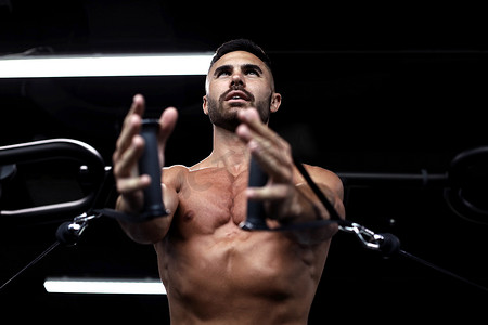 防抱死制动系统摄影照片_健康和肌肉发达的男人在健身房的块模拟器上训练胸肌。