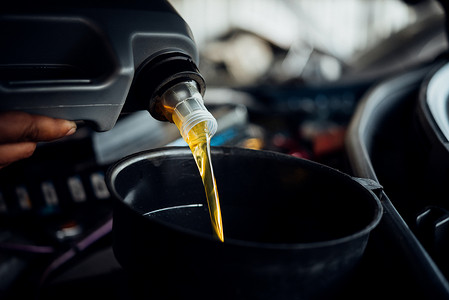 汽车修理工填充新鲜的润滑油发动机油