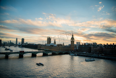 日落时的伦敦天际线景观，包括著名地标、大本钟、议会大厦和泰晤士河上的船只，以及美丽的蓝天和黄天。
