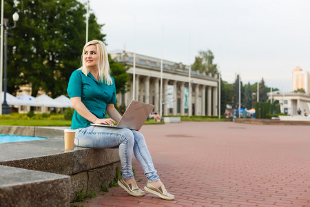 学生找工作摄影照片_夏天在城市公园里用笔记本电脑找工作的女人