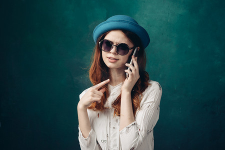 蓝帽技术摄影照片_戴蓝帽的时尚女性手握电话通信技术