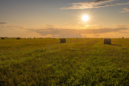 夏日傍晚夕阳下的干草堆田野。