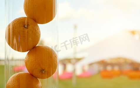 三个有机多汁的甜健康橙子，特写，在色彩缤纷的自然背景中的水晶花瓶中