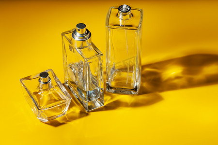 淡黄色背景上的香水玻璃瓶。