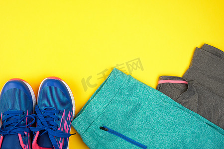 衣服平铺摄影照片_黄色背景上的蓝色女式运动鞋和运动服