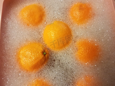 粉红色塑料桶中肥皂水中的橙子