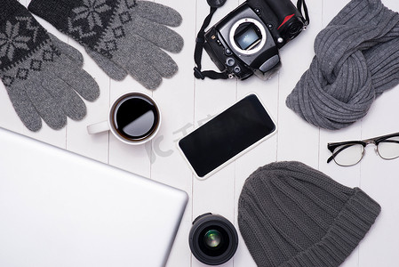 冬季男装摄影照片_男士冬季休闲装，配有相机、咖啡杯、笔记本电脑、智能手机和木制背景眼镜