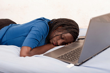 详细策略摄影照片_女人睡在笔记本电脑前的床上