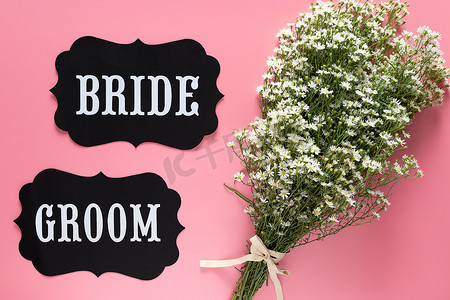 新娘和新郎在粉红色背景上的文字签名，装饰着白花花束，复古风格。