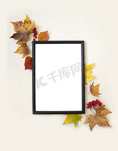 创意邀请函背景摄影照片_米色背景上的空白模拟相框、秋叶和浆果。