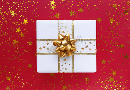 白色礼品盒，红色背景上有金色蝴蝶结和星星。