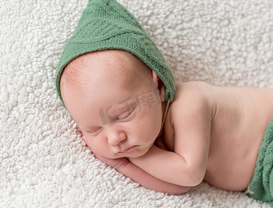 睡在绿色精灵帽子和内裤里的可爱新生儿