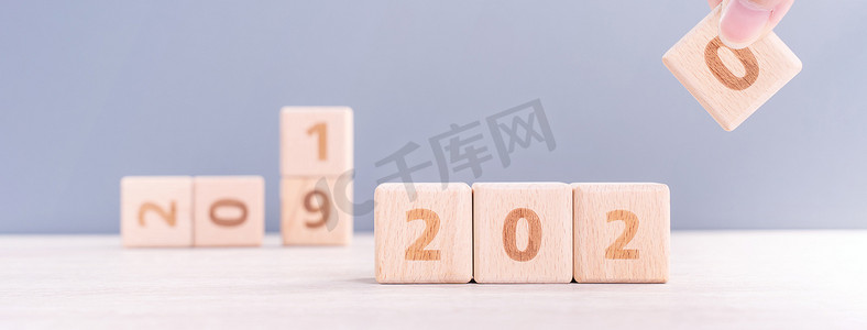 摘要2020年和2019年新年倒计时设计概念-妇女在木桌和蓝色背景上拿着木块立方体，特写，复制空间。