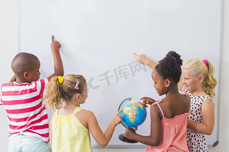 男女学生摄影照片_孩子们在教室里学习地球仪