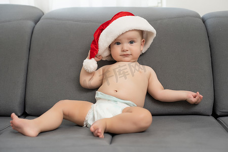 圣诞帽的婴儿摄影照片_戴着圣诞帽的可爱男婴