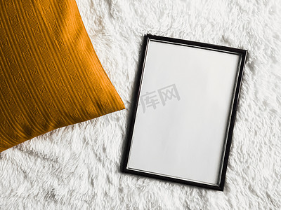 带有空白复制空间的黑色薄木框作为海报照片打印模型、金色垫枕和蓬松的白色毯子、平躺背景和艺术产品