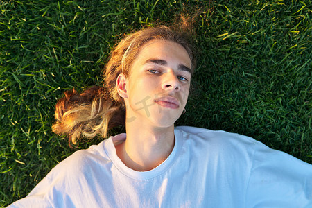 16、17 岁帅哥在绿草上的特写脸，顶视图