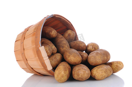 赤褐色摄影照片_赤褐色土豆从篮子里溢出
