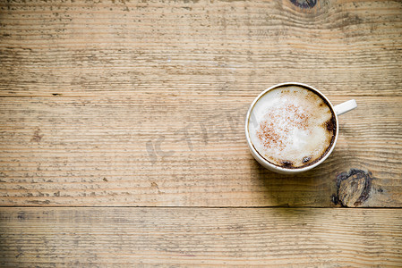 木桌上一杯拿铁咖啡或卡布奇诺咖啡。