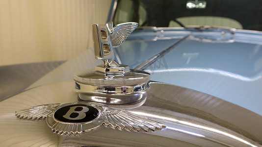 飞驰的汽车摄影照片_1950 年飞驰豪华轿车引擎盖上的宾利 S1 徽章特写。