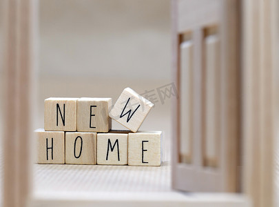 New Home 文本以木制立方体背景书写，带有舒适小房子的象征，背景设计模糊，购买房地产，抵押贷款，业主概念背景