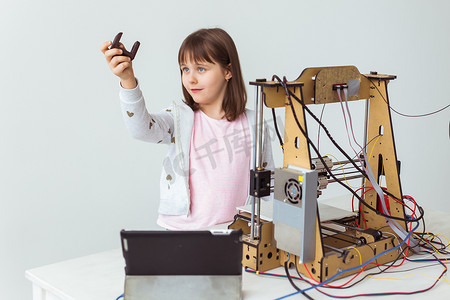 带着 3D 打印快门色调的可爱女孩正在看着她的 3D 打印机打印她的 3D 模型。