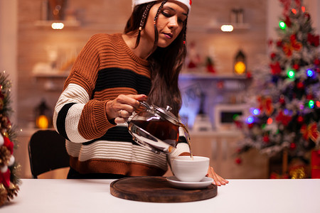 穿冬装的女人从水壶里倒茶