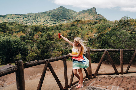 在毛里求斯岛、自然保护区、Chamarel Sands.Mauritius 岛的群山背景下，一个手里拿着一罐红饮料的小女孩