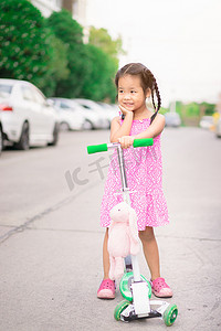 街上骑着摩托车和洋娃娃的亚洲小女孩的肖像