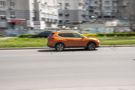 日产摄影照片_乌克兰，基辅 - 2021 年 4 月 26 日：橙色日产 Rogue 汽车在街上行驶。