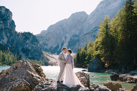 新娘和新郎站在石头上俯瞰意大利的 Lago di Braies。