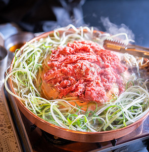 首尔韩国餐厅的牛肉烧烤烤肉，铜锅上的生活方式新鲜韩国美食，配上葱片，特写，复制空间